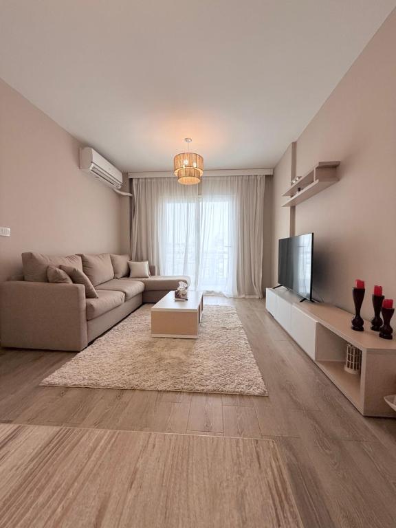 a living room with a couch and a tv at Comfy Hotel Apartament in Madinaty