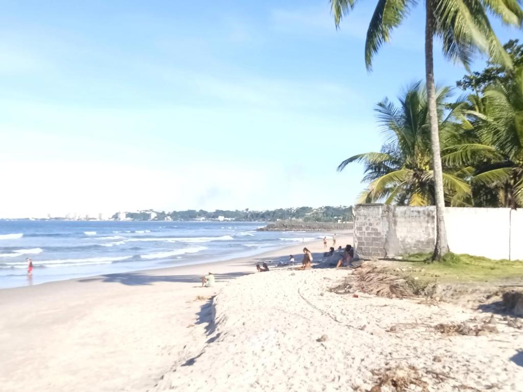 a beach with palm trees and people sitting on the sand at EBORA Afro Cultural in Ilhéus