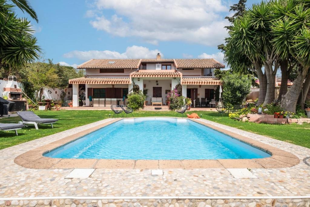 a house with a swimming pool in front of a yard at Beachfront villa with direct access -Private pool & Zen Area in Quartu SantʼElena