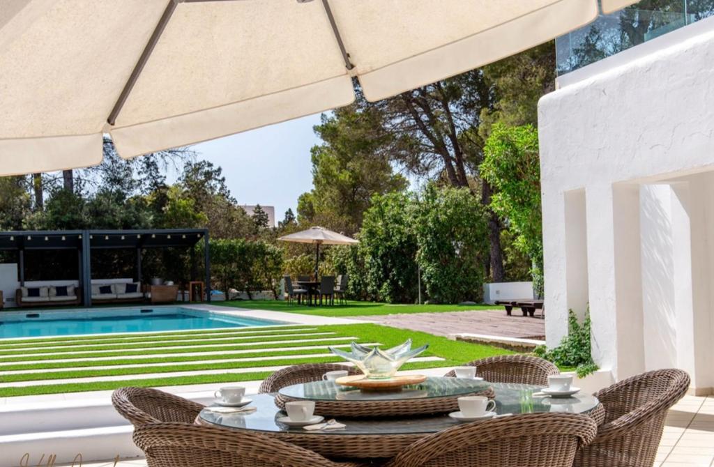 Un patio con mesa y sillas y una piscina. en Villa cala tarida, en Cala Tarida