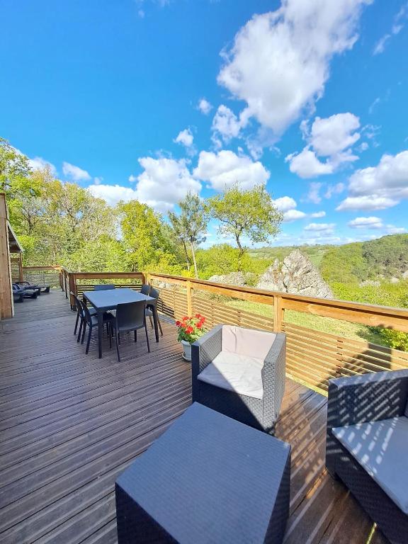 une terrasse avec une table et des chaises. dans l'établissement St Léonard des bois le chalet paisible, à Saint-Léonard-des-Bois