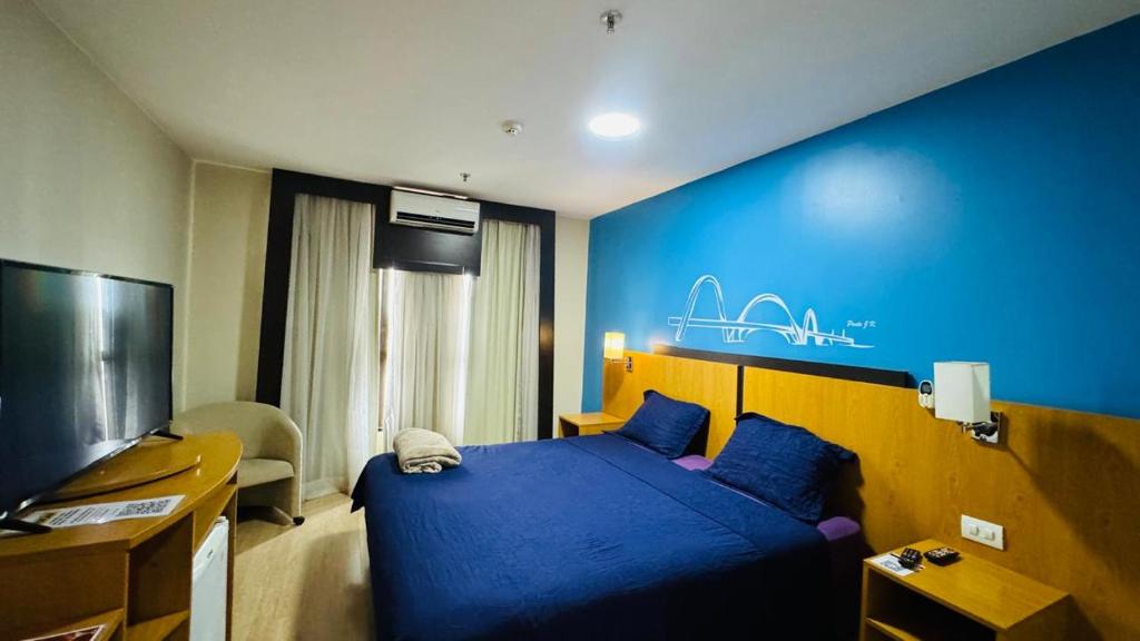 a bedroom with a bed and a blue wall at Flat aconchegante in Brasilia