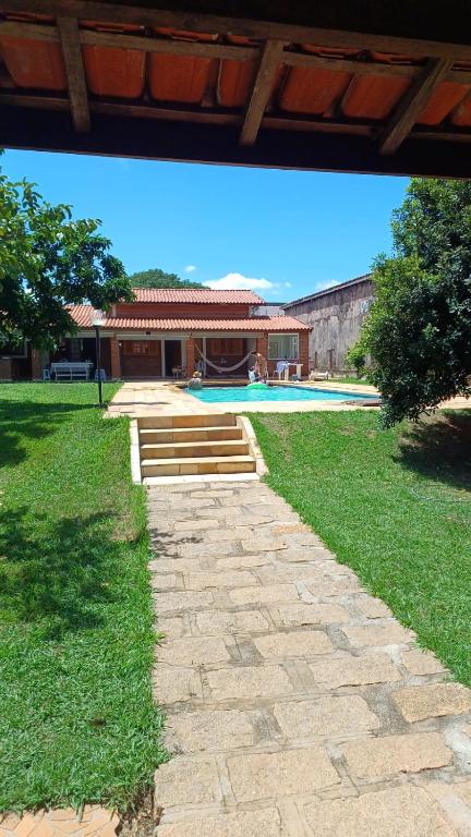 a stone path leading to a house with a swimming pool at Chácara Vivenda Aconchego in Itupeva