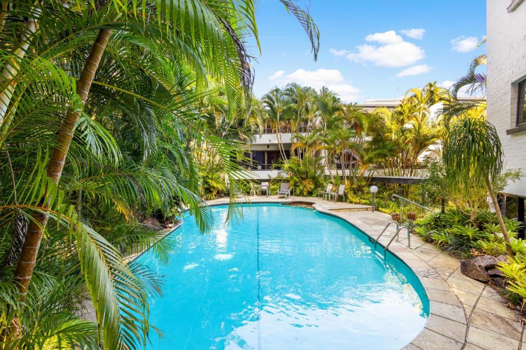 Una gran piscina con palmeras frente a un edificio. en 7 28 Viewland Drive Noosa Heads, en Noosa Heads