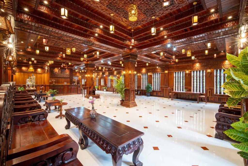 a large room with a wooden ceiling and tables at Puok Resort in Phumĭ Puŏk Chăs