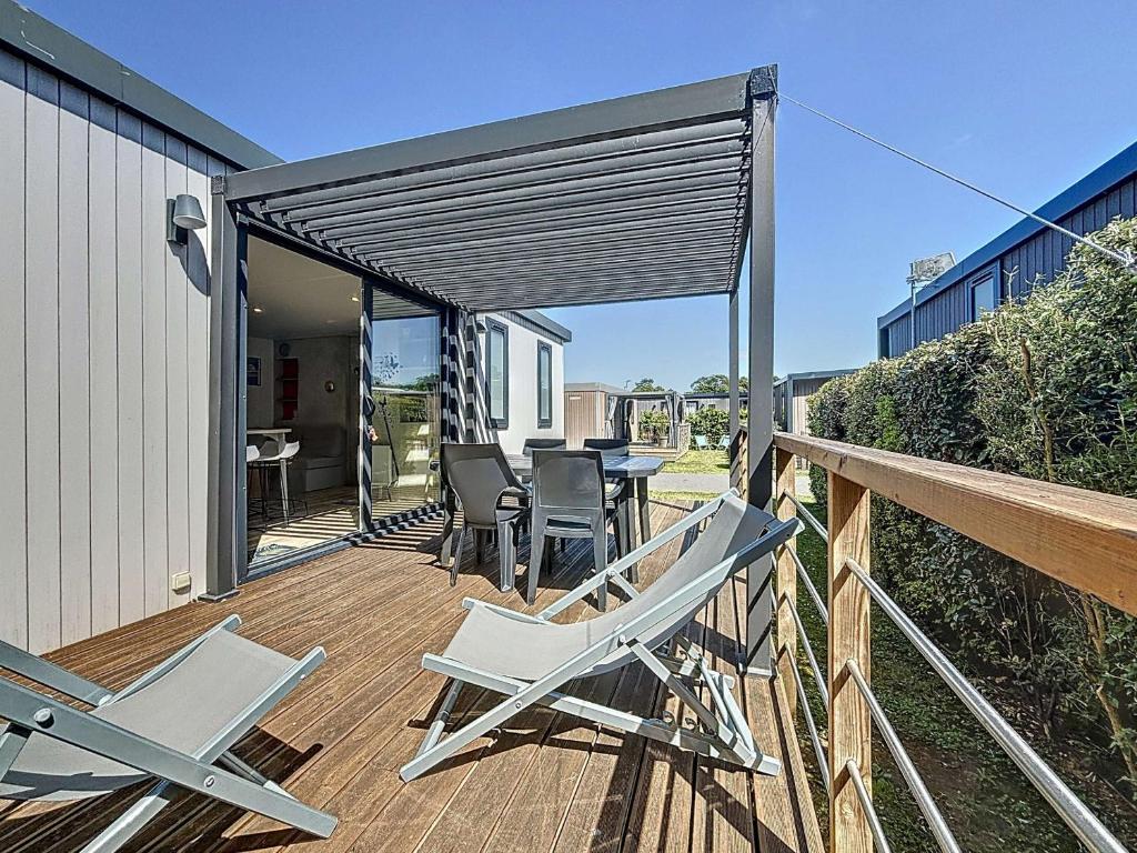 une terrasse avec des chaises, une table et un auvent dans l'établissement Mobil-home Keywest: 2 chambres, 2 sdb, plage à 200m, piscine chauffée, fitness, parking, Wi-Fi inclus - FR-1-361A-27, à Jullouville
