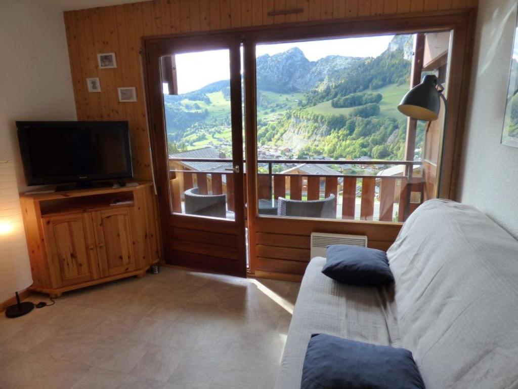 une chambre avec un lit, une télévision et un balcon dans l'établissement Studio rénové 4 pers - accès direct aux pistes - FR-1-458-224, au Grand-Bornand