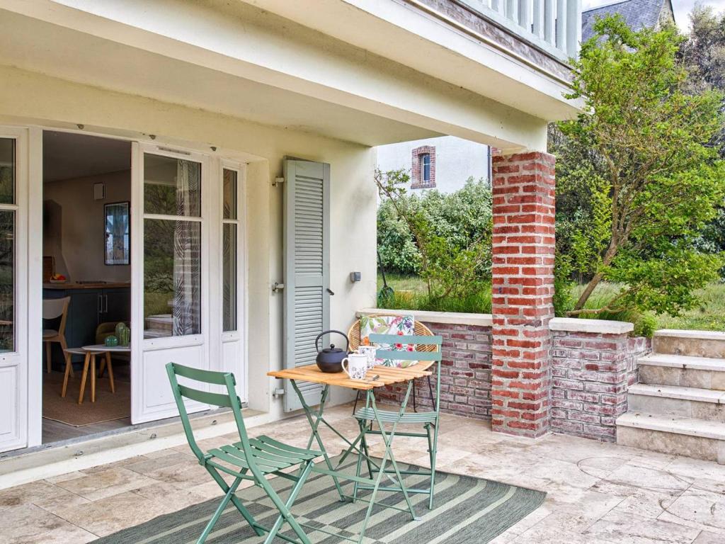 un patio avec une table et des chaises sur un porche dans l'établissement Villa VertMer : Évasion paisible entre plénitude et plage - FR-1-788-71, à Varaville