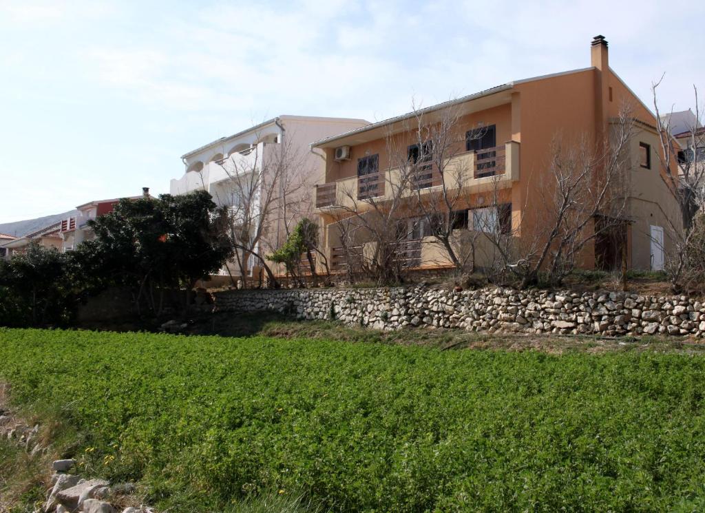 une maison avec un mur en pierre à côté d'un champ dans l'établissement Apartments Nada, à Pag