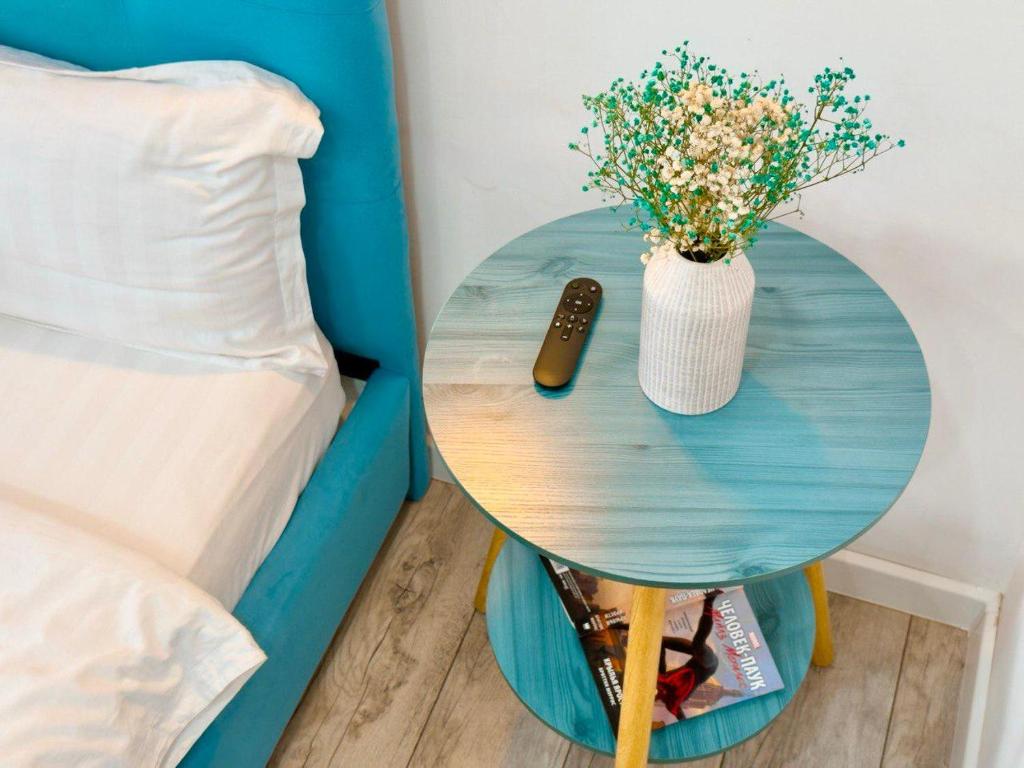 a table with a remote and a vase of flowers on a bed at Ауельбекова 120 in Kokshetau
