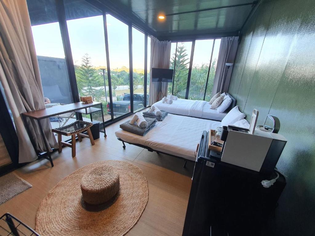 Un dormitorio con una cama y una mesa en una habitación con ventanas. en Nara Black Mountain, en Ban Tha Chang