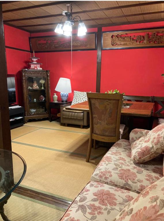 a bedroom with red walls and a bed and a table at ゲストハウス町家はま in Izumi-Sano