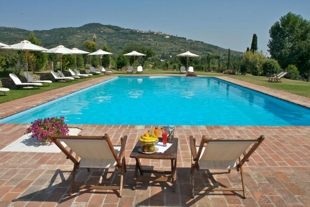 a swimming pool with two chairs and a table next to it at Relais Villa Baldelli in Cortona