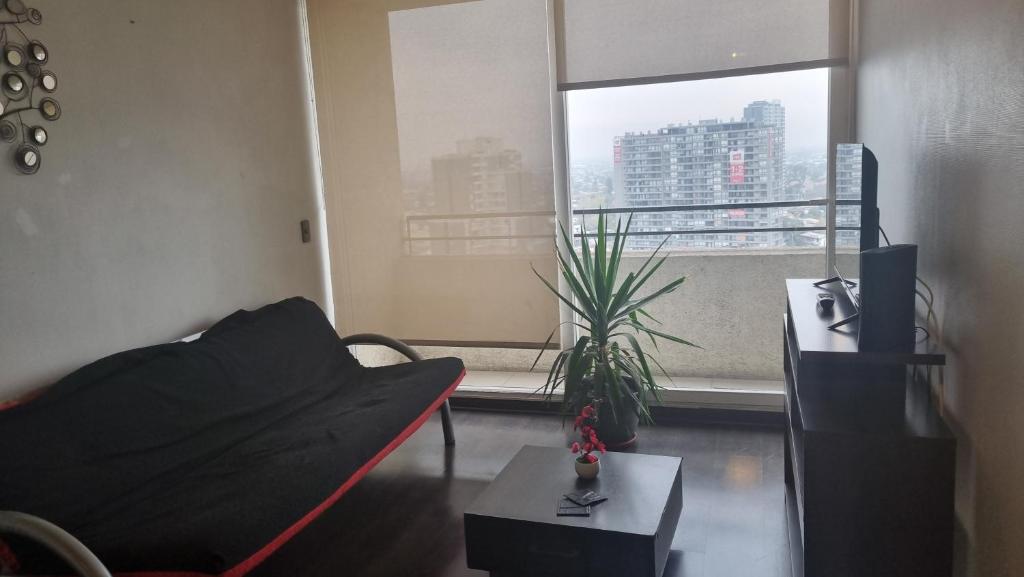 a living room with a couch and a table and a window at Departamento Centro de La Florida in Santiago