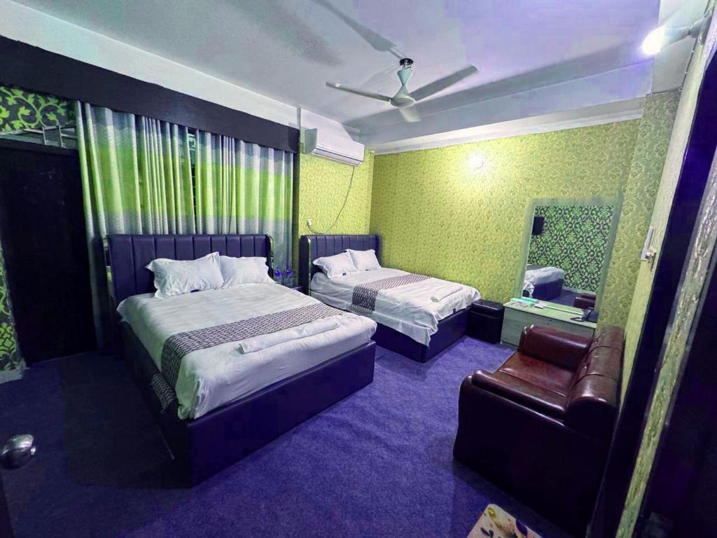 Un dormitorio con dos camas y una silla y un espejo. en Hotel Ebraj Sylhet, en Sylhet