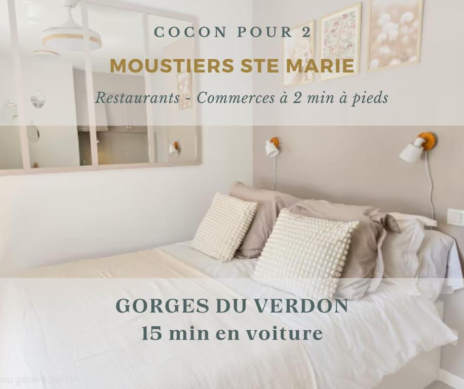 a white bedroom with a bed and a mirror at Cocon pour 2 - vue sur le clocher in Moustiers-Sainte-Marie