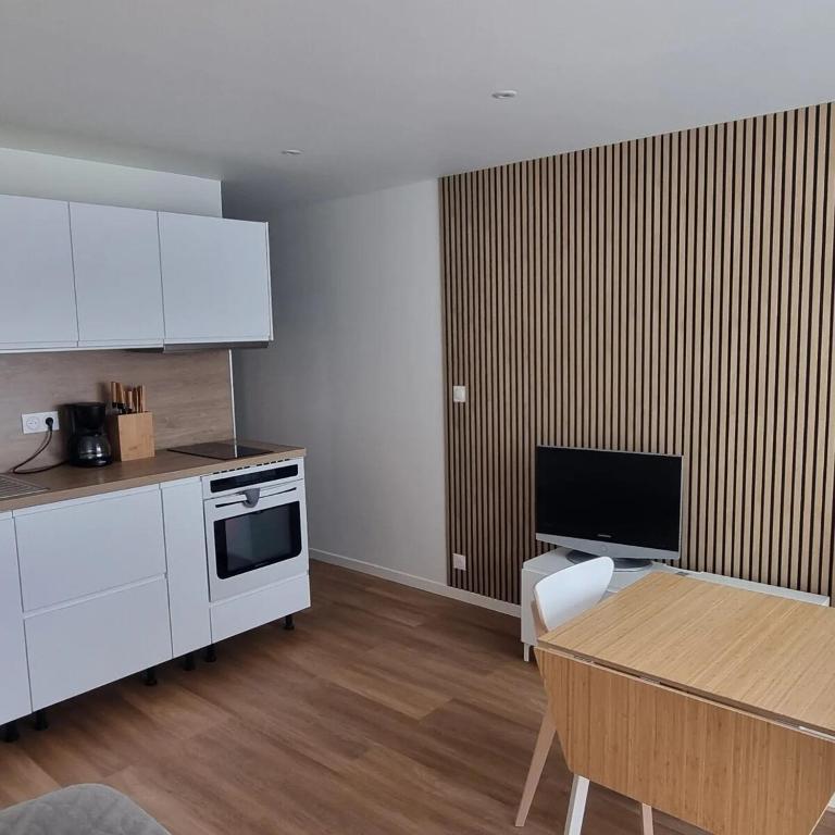 une cuisine avec des armoires blanches et une table et une table et une télévision dans l'établissement Appartement, à Aix-en-Provence