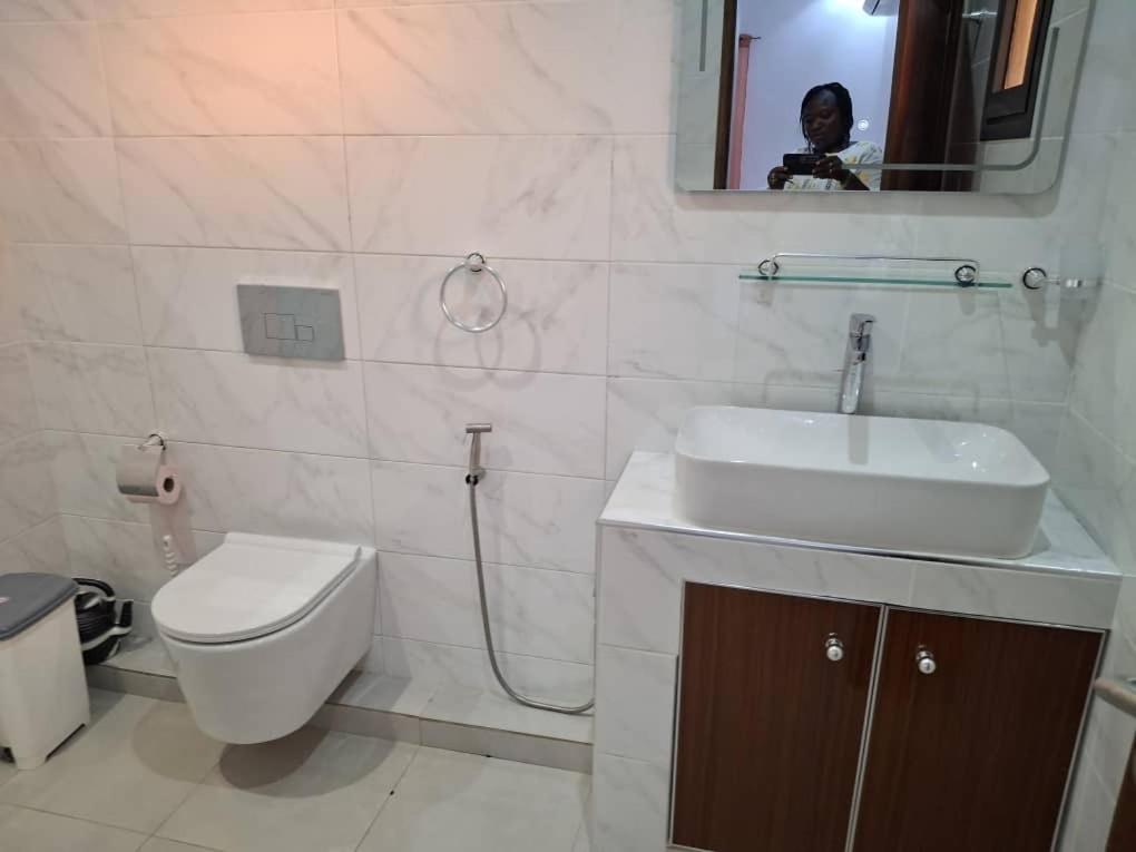 a bathroom with a sink and a toilet and a mirror at Villa Hélène in Nianing