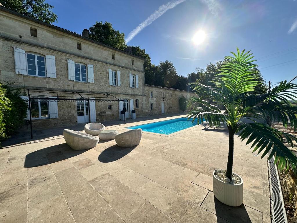 un cortile con una palma e una piscina di Ancien Château viticole a Bourg-sur-Gironde