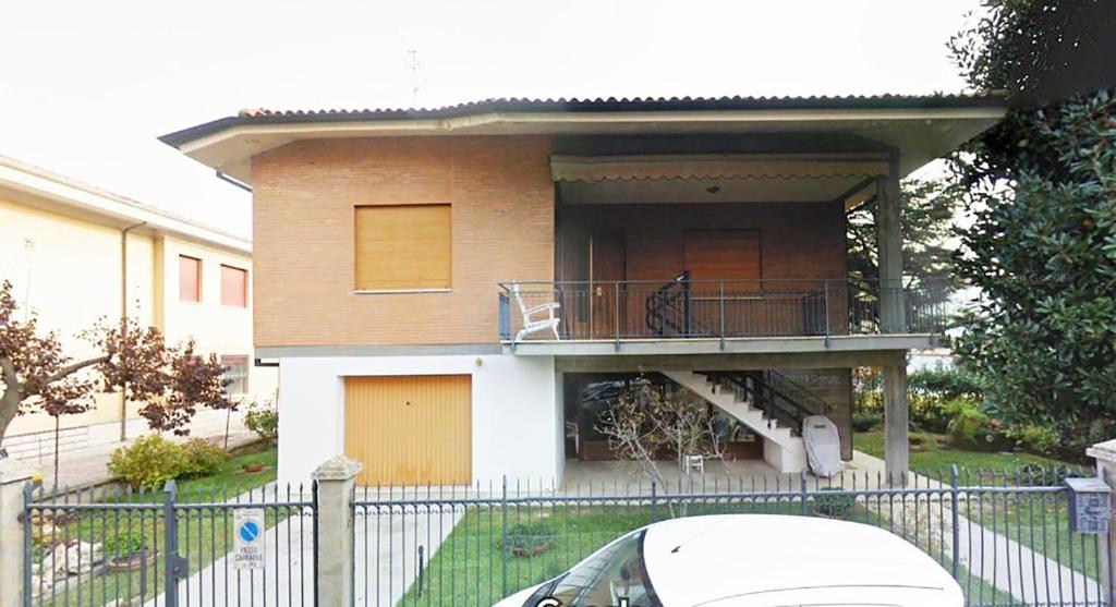 a house with a balcony and a car parked in front at Appartamento mare in Cesenatico