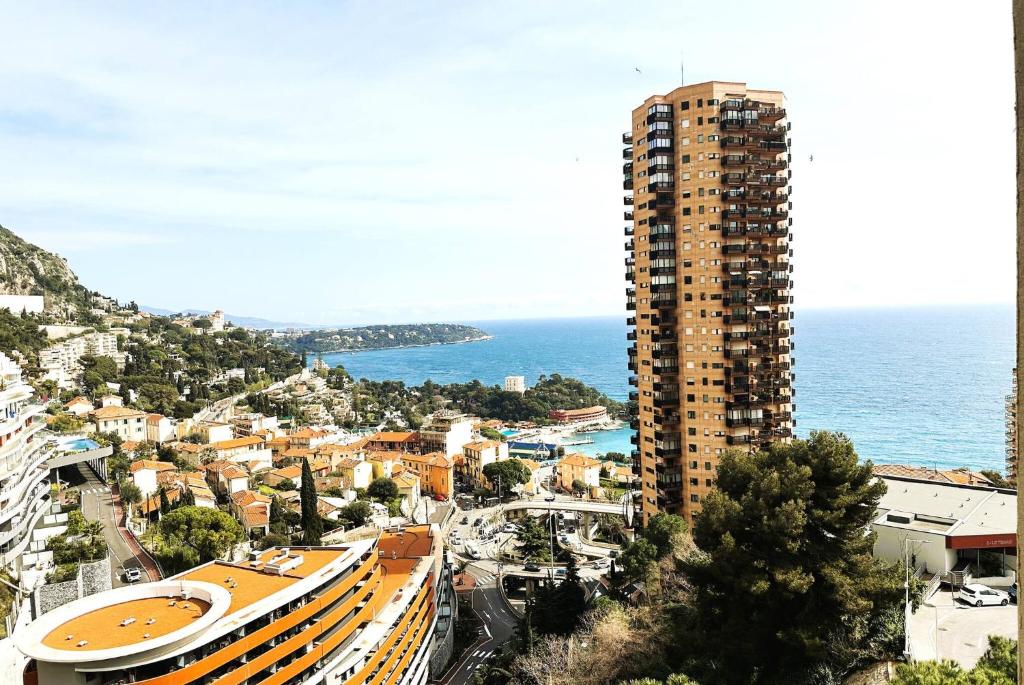 une ville avec un grand bâtiment à côté de l'océan dans l'établissement STUDIO BEAUSOLEILMONACO TERRASSE VUE MER Clim et Accès Piscine, à Beausoleil