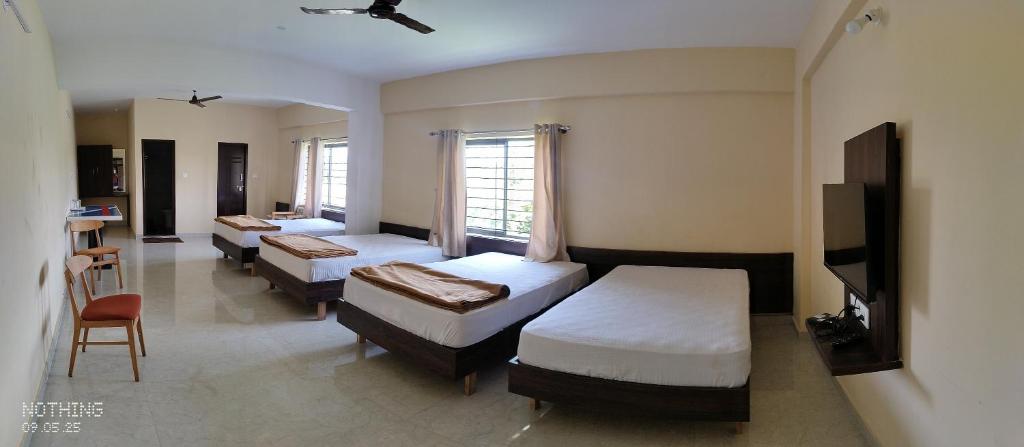 BelagulaHotel White Palace的一间设有三张床和电视的房间,一间设有