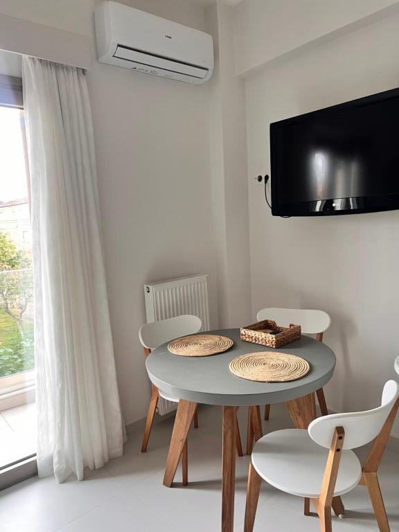 jadalnia ze stołem i krzesłami oraz telewizorem w obiekcie Fays luxury apartments by the sea w mieście Finikounda