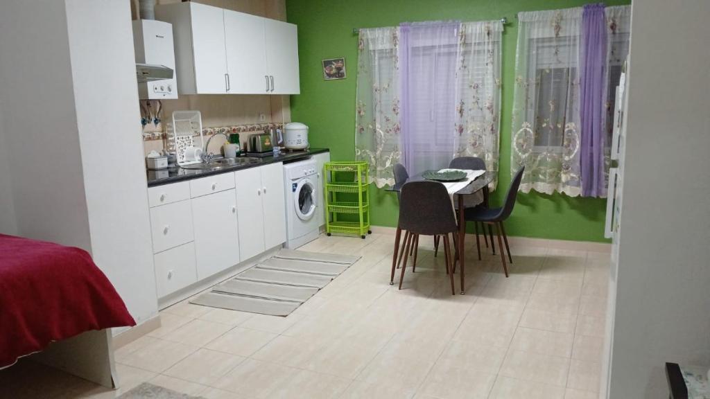 a kitchen with green walls and a table and chairs at Charming T1 apartment in Seixal in Aldeia de Paio Pires