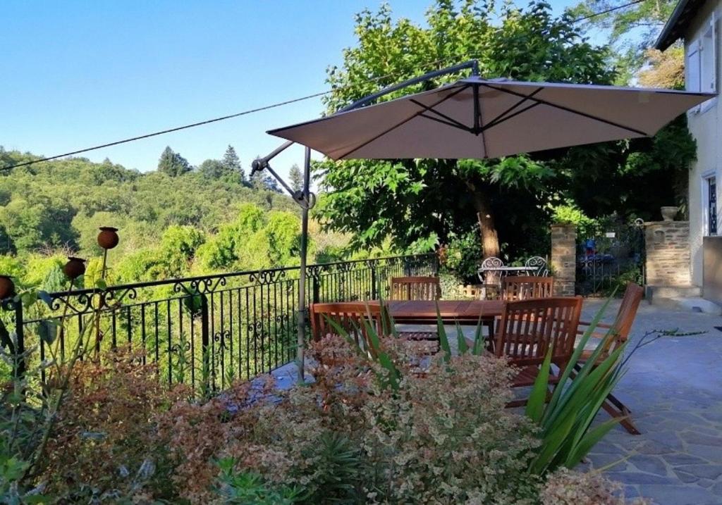 - une table et des chaises avec un parasol dans le jardin dans l'établissement Maison Rocher, à Ségur-le-Château