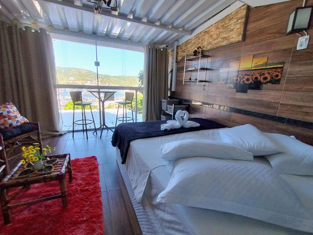 una camera da letto con un letto e un balcone con un tavolo di PraiAna Loft Arraial do Cabo ad Arraial do Cabo