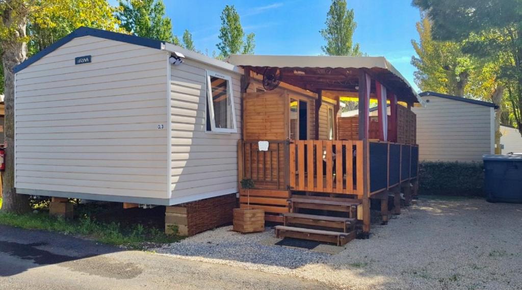 a tiny house with a porch and a staircase at Mobilhome 6-8 pers - 3 ch - 1 sdb - Parc Aquatique in Vias