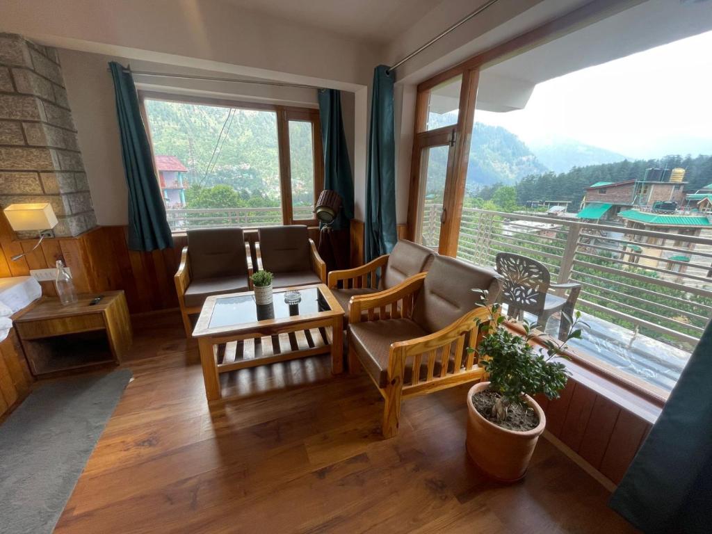 a living room with chairs and a table and a large window at Drifters Inn - The Hidden Tribe in Manāli
