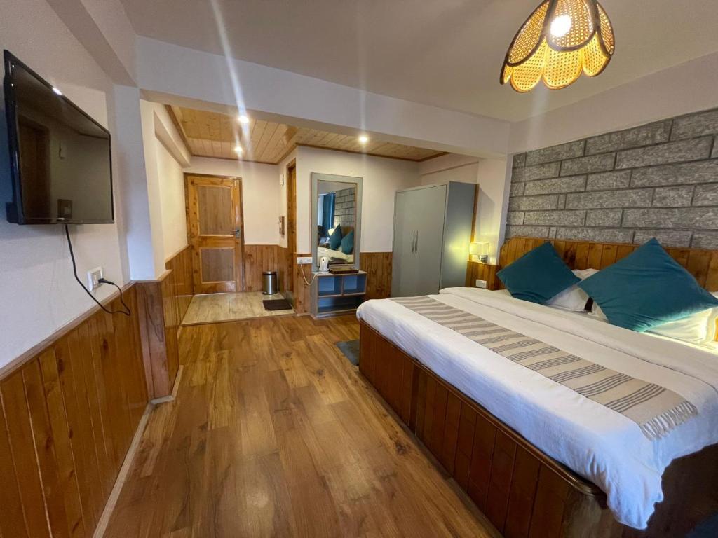a bedroom with a large bed and a television at Drifters Inn - The Hidden Tribe in Manāli