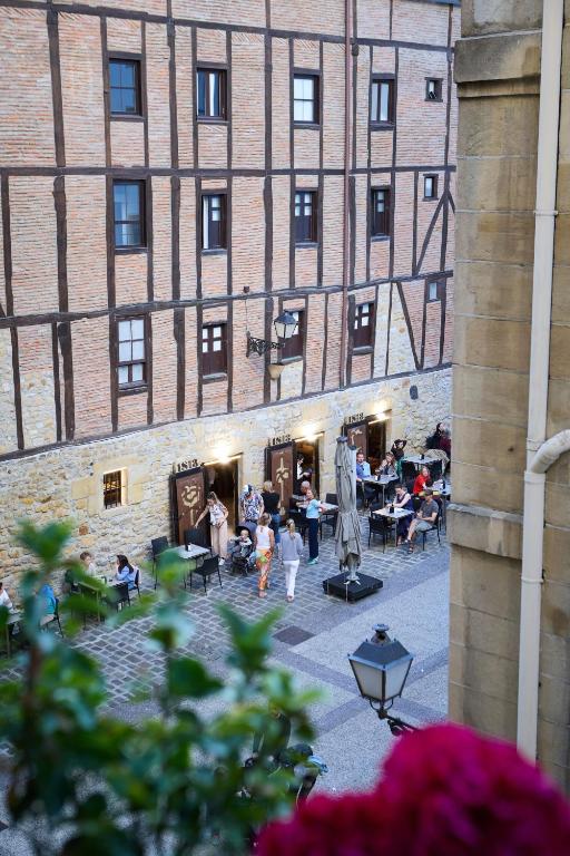 un grupo de personas sentadas frente a un edificio en Pensión San Jerónimo, en San Sebastián