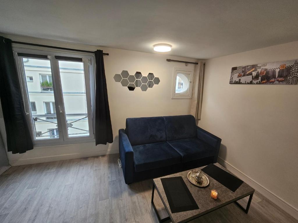un salon avec un canapé bleu et une fenêtre dans l'établissement Studio très calme, à Paris