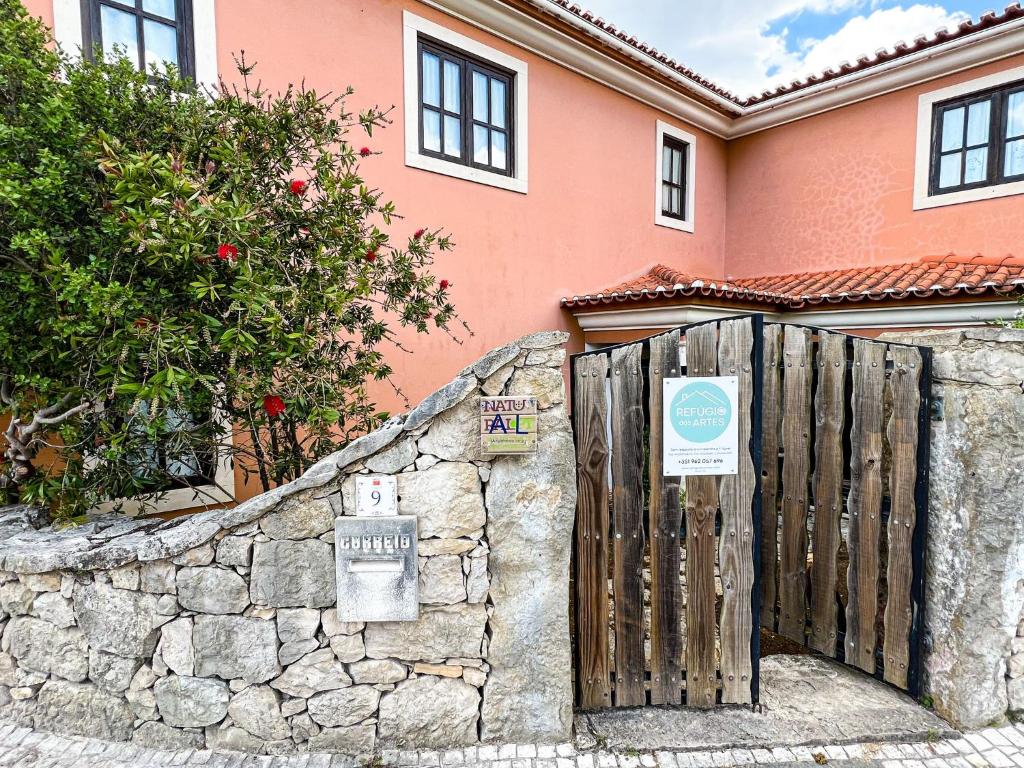 a fence in front of a pink house at Refúgio das Artes Guesthouse in Porto de Mós