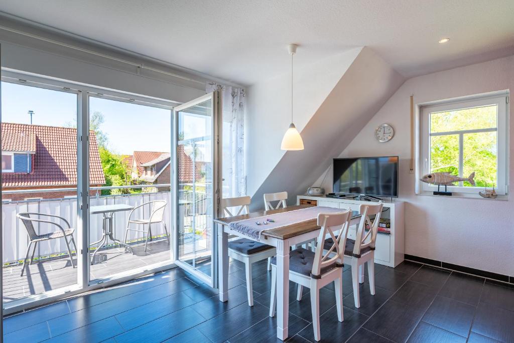 a dining room with a table and chairs and a balcony at Arielle in Norddeich