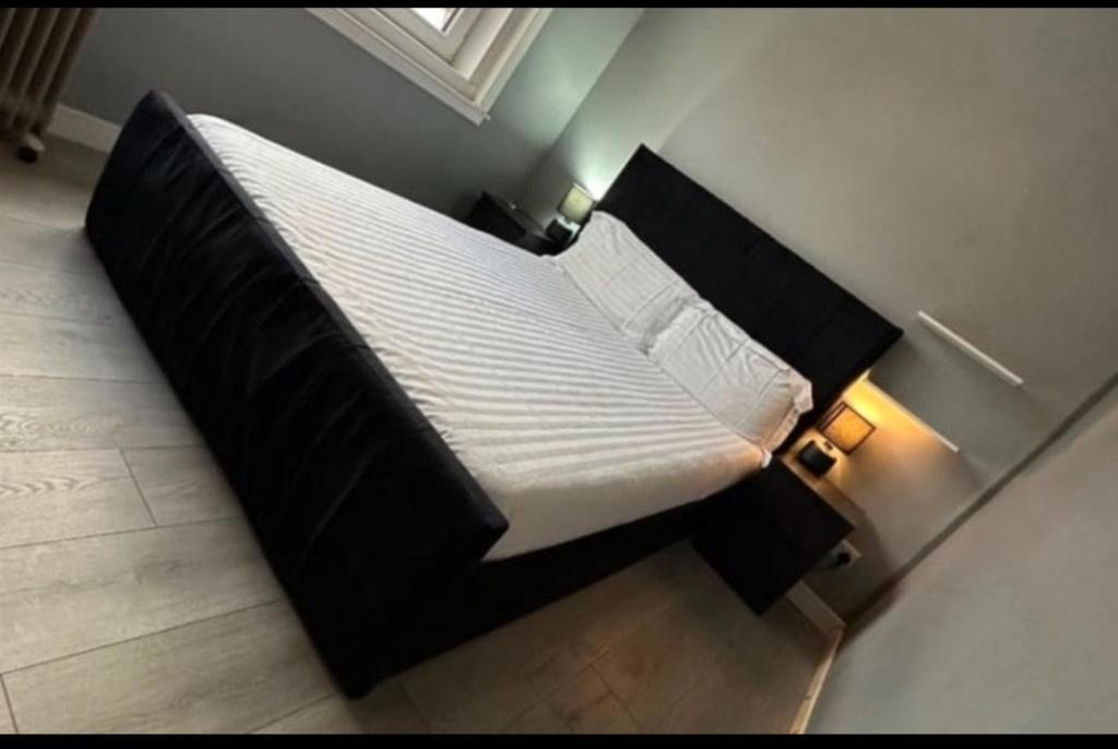 un letto con struttura nera e lenzuola e cuscini bianchi di Portobello sleep and eat a Edimburgo