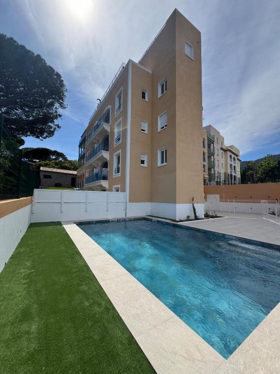 un immeuble avec une piscine devant un immeuble dans l'établissement Bel Appartement Tout Neuf, à Cavalaire-sur-Mer