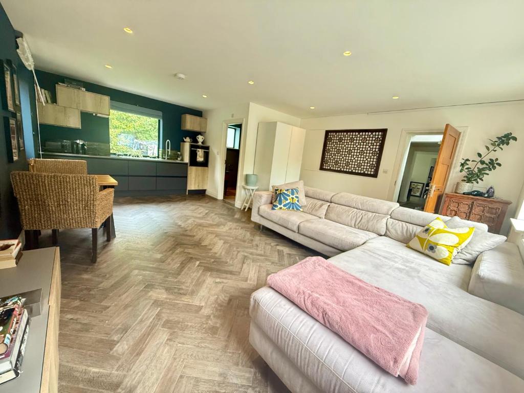 a large living room with a couch and a kitchen at Studio with kitchen nestled lovely wooded cul du sac in New Malden