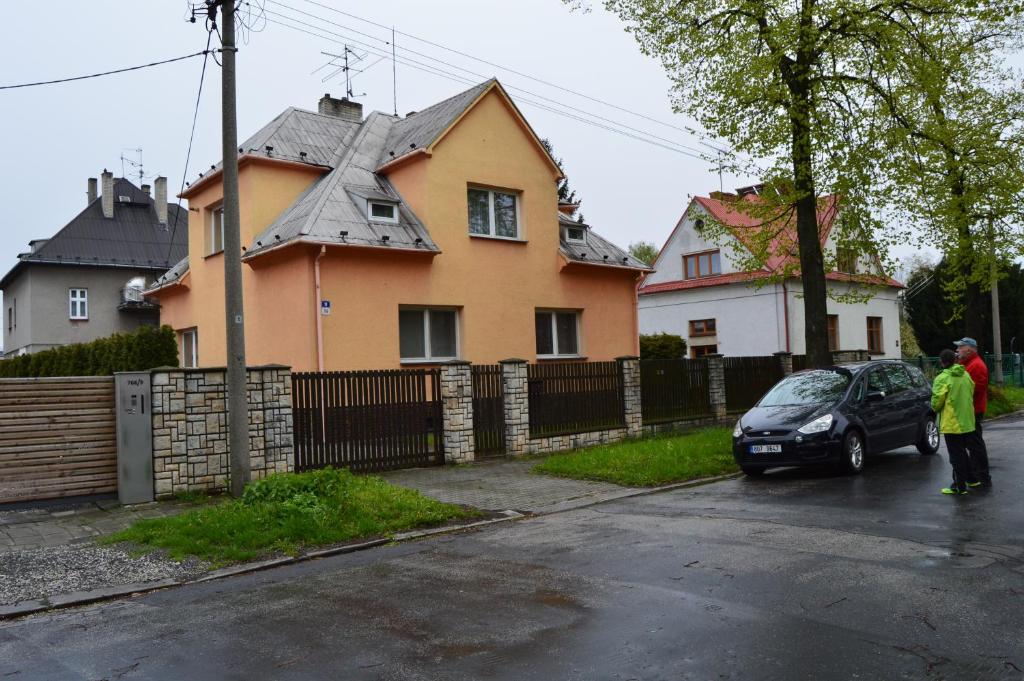 Un homme debout à côté d'une voiture devant une maison dans l'établissement Vila Paradise, à Ostrava