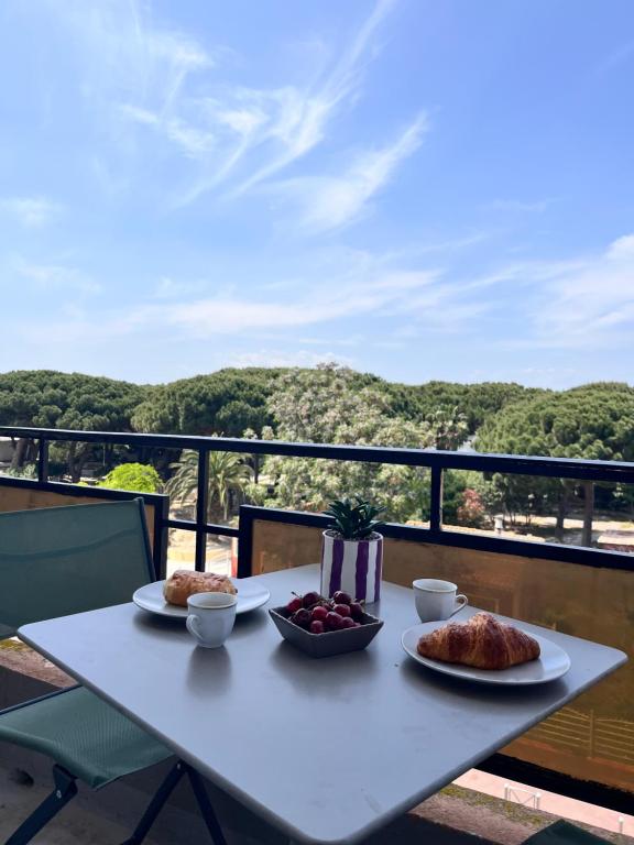 - une table blanche avec de la nourriture sur le balcon dans l'établissement Appartement cosy à 2 pas de la mer, idéal familles, à Canet