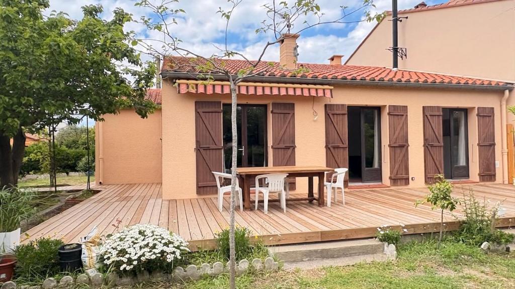 une terrasse en bois avec une table et des chaises devant une maison dans l'établissement Belle villa rénovée, vue sur les Albères, à Argelès-sur-Mer