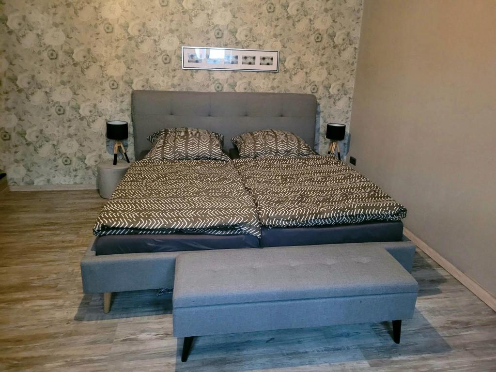 a bedroom with a large bed with a blue foot stool at Moderne Ferienwohnung in der Altstadt in Eschwege