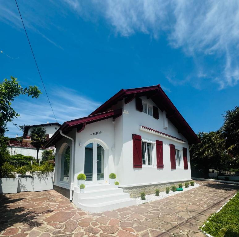 a white house with red shutters on it at Maison - St Jean de Luz - Proche de la plage in Saint-Jean-de-Luz