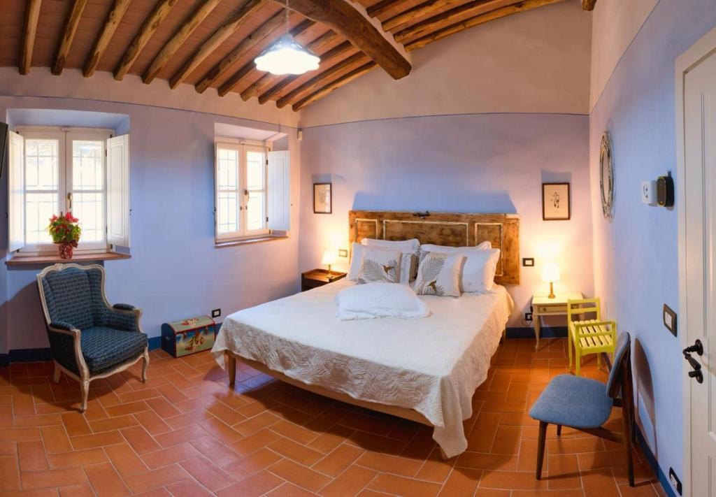 a bedroom with a large bed and two chairs at Casale la Poiana in Lucca