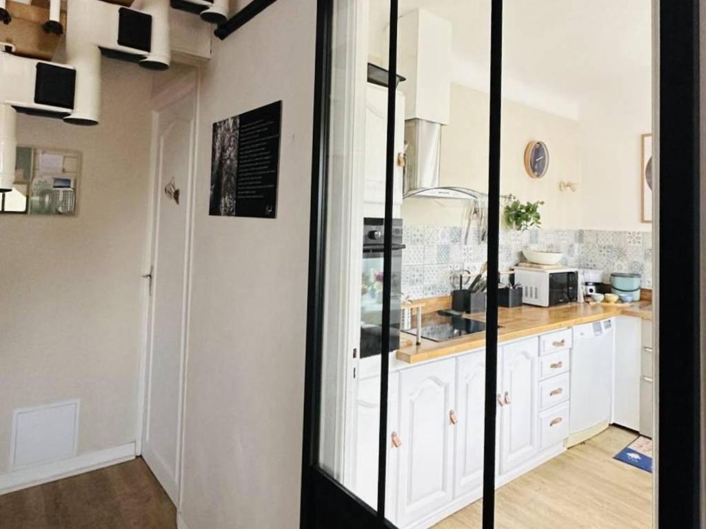 une cuisine avec des armoires blanches et un comptoir dans l'établissement Maison 3*** à 300m de la plage, jardin privé, Wifi inclus, proche commerces, 6 pers., non-fumeurs - FR-1-542-47, à Pleumeur-Bodou