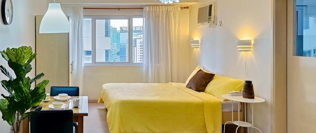 a hotel room with a yellow bed and a window at Charming Modern Condo in BGC in Manila
