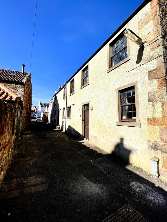 an empty street in front of a brick building at Rose Wynd Cottage-Close to beach in Crail