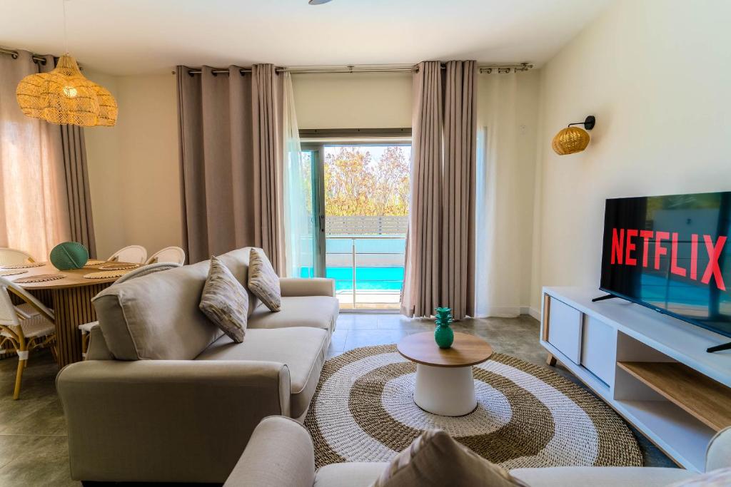 a living room with a couch and a tv at Salty Breeze in Flic-en-Flac
